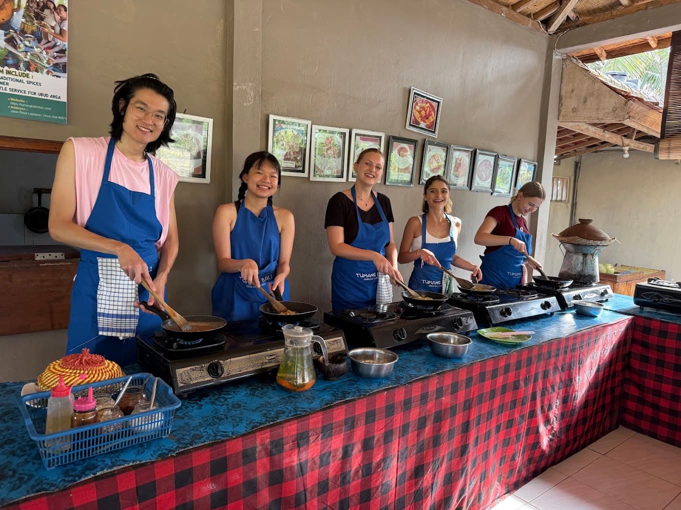 A small group in blue aprons seated along a class table with bowls of ingredients